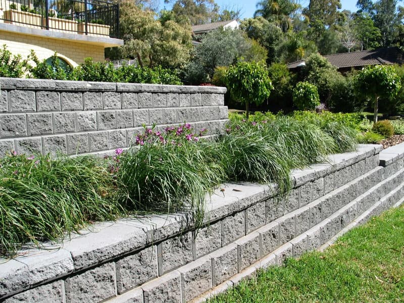 Natural stone retaining wall with integrated landscaping creating terraced garden areas in Sydney by Nazscapes