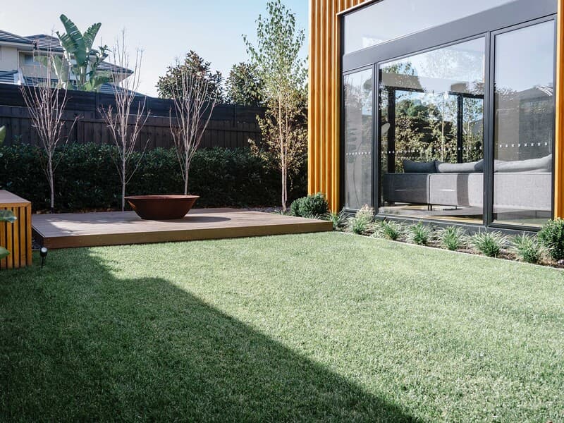 Modern Sydney backyard with hardwood deck, fire bowl, and ornamental tree planting completed by Nazscapes